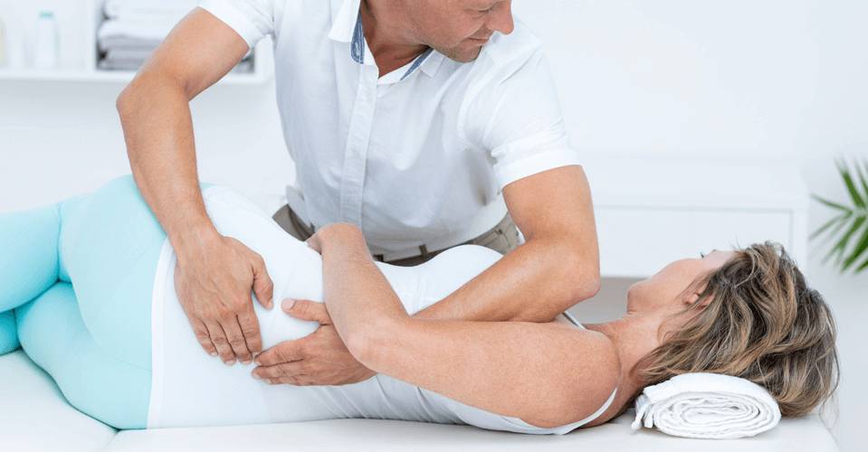 Male Physical therapist treating female patient with lower back pain