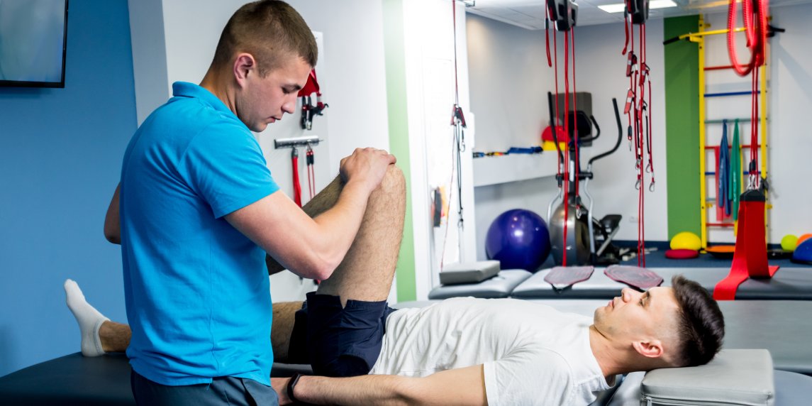 Rehabilitation therapy. Physiotherapist working with young male patient in the rehabilitation center. Treatment pain in spine