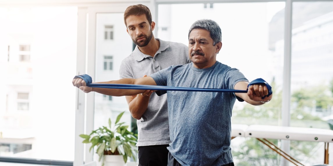 Physiotherapy, stretching and band with old man and doctor for training, rehabilitation and injury. Medical, healing and healthcare with expert and patient for consulting, help and fitness