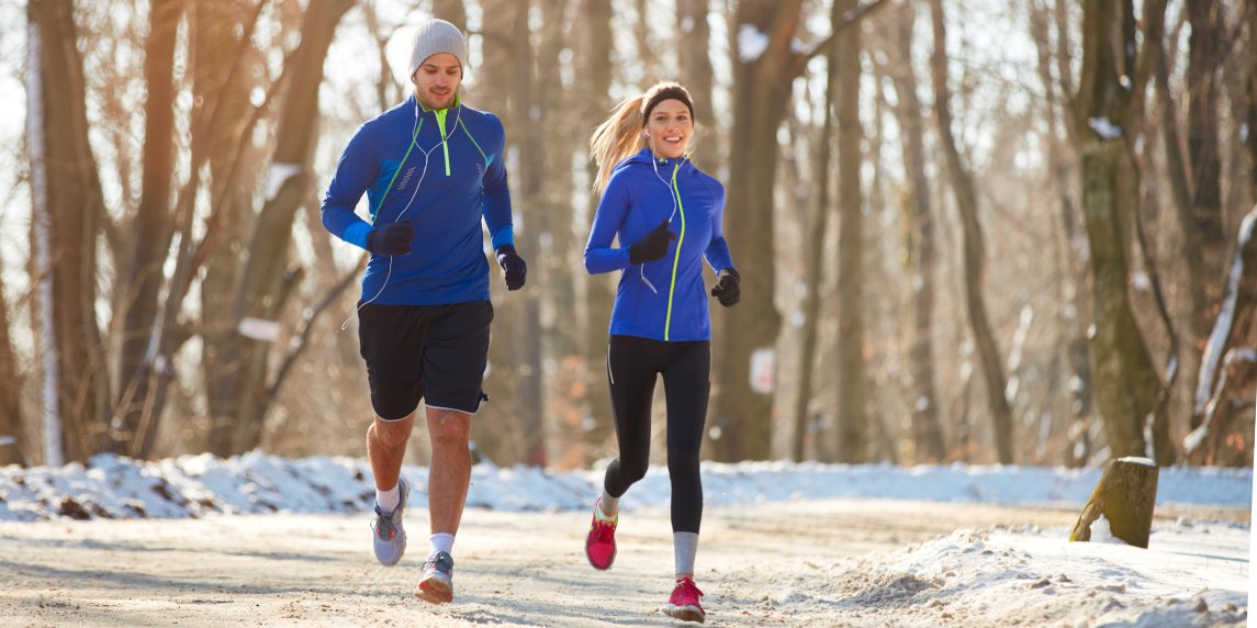 Young couple in the winter running together in nature