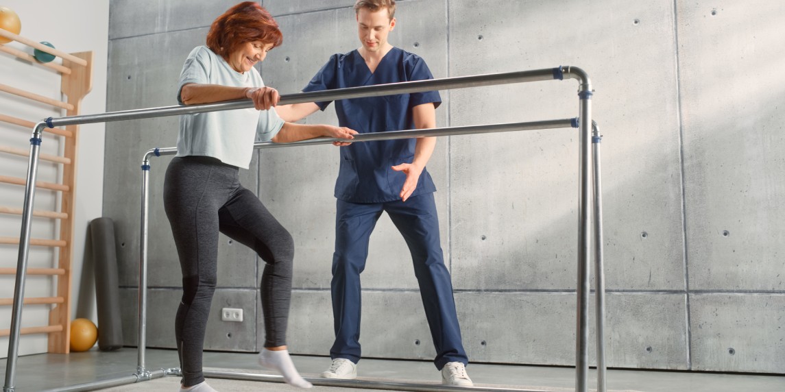 Strong Senior Woman with Leg Injury Successfully Walks Holding Parallel Bars.