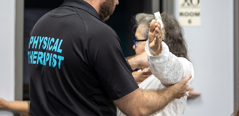 A XO physical Therapy worker assisting a woman in a room, highlighting support in managing chronic pain during Texas heat.