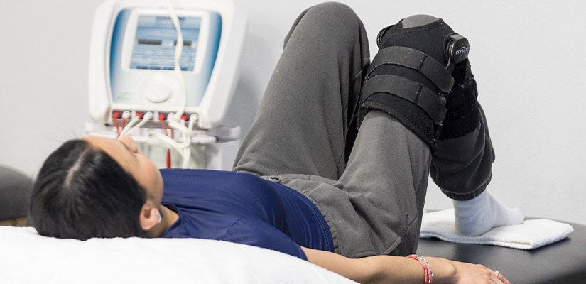 A woman lying on a bed with a leg brace, highlighting themes of fall hydration and pain relief.