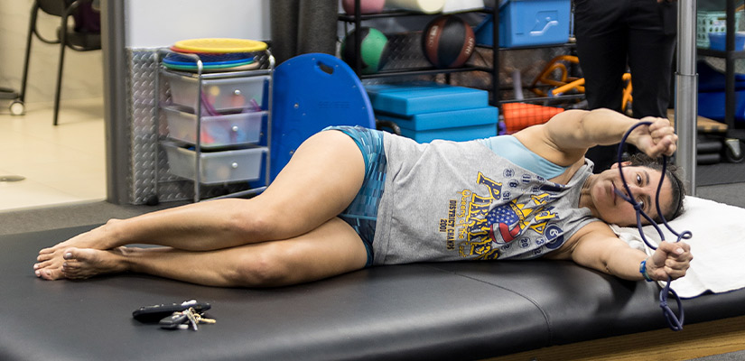 A woman resting on a massage table with her legs up, emphasizing fall hydration and pain relief techniques.
