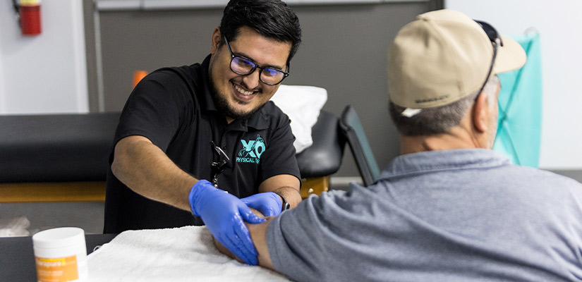 An XO therapist expert draws blood from a man seated in a medical office, focusing on the procedure.