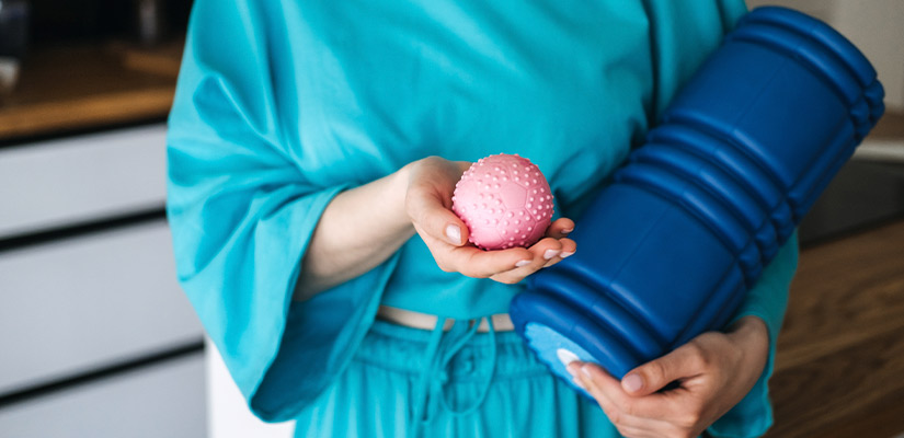 A woman with a pink ball and blue yoga mat, illustrating how physical therapy can help reduce holiday-related discomfort.