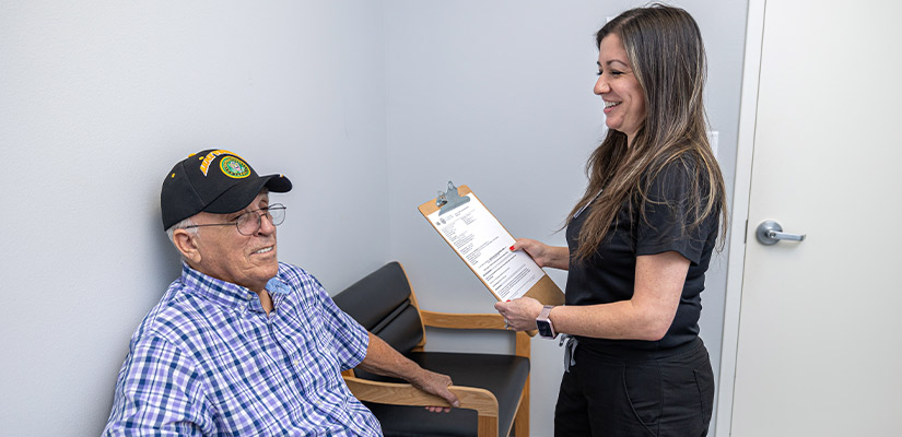  In a vestibular physical therapy waiting room, a woman speaks with an elderly man.