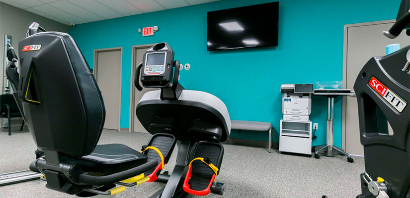 Interior of a gym with various exercise equipment and a television, associated with Pain Management in Mission, TX.