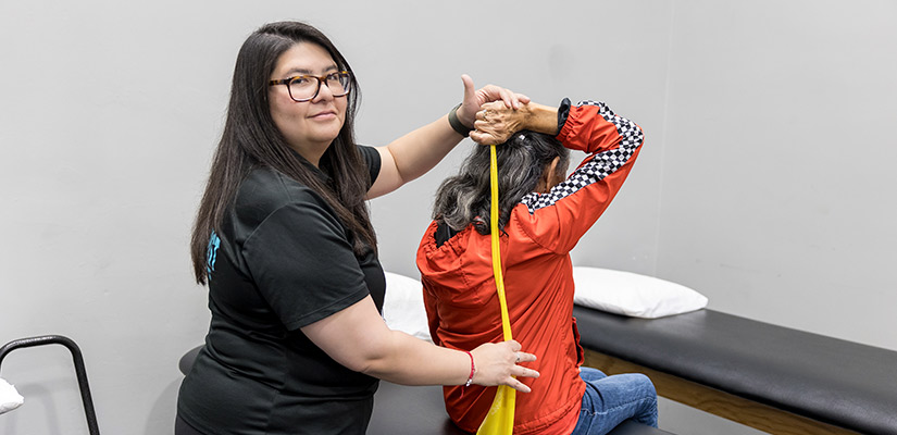 A woman receives back stretching treatment from a physical therapist in a McAllen clinic focused on pain management.