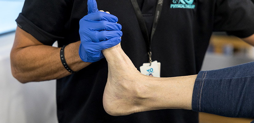 A healthcare professional checks a patient's foot as part of pain management therapy in McAllen.