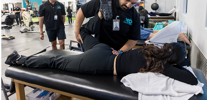 A man assists a woman with a back stretch, emphasizing techniques for alleviating back pain in a wellness environment.