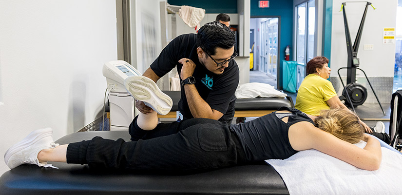 A man and a woman engage in a physical therapy session aimed at alleviating back pain at XO Physical Therapy in Weslaco.