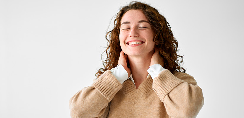 A woman with a smile holds her neck, symbolizing options for neck pain relief treatments in McAllen.