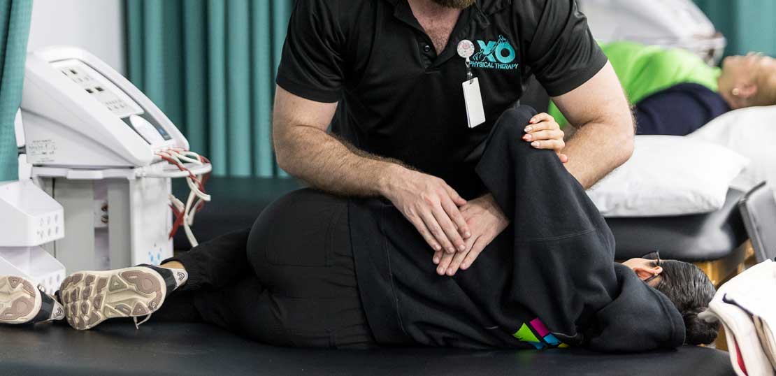A physical therapist guides a patient through exercises, emphasizing support and rehabilitation techniques.