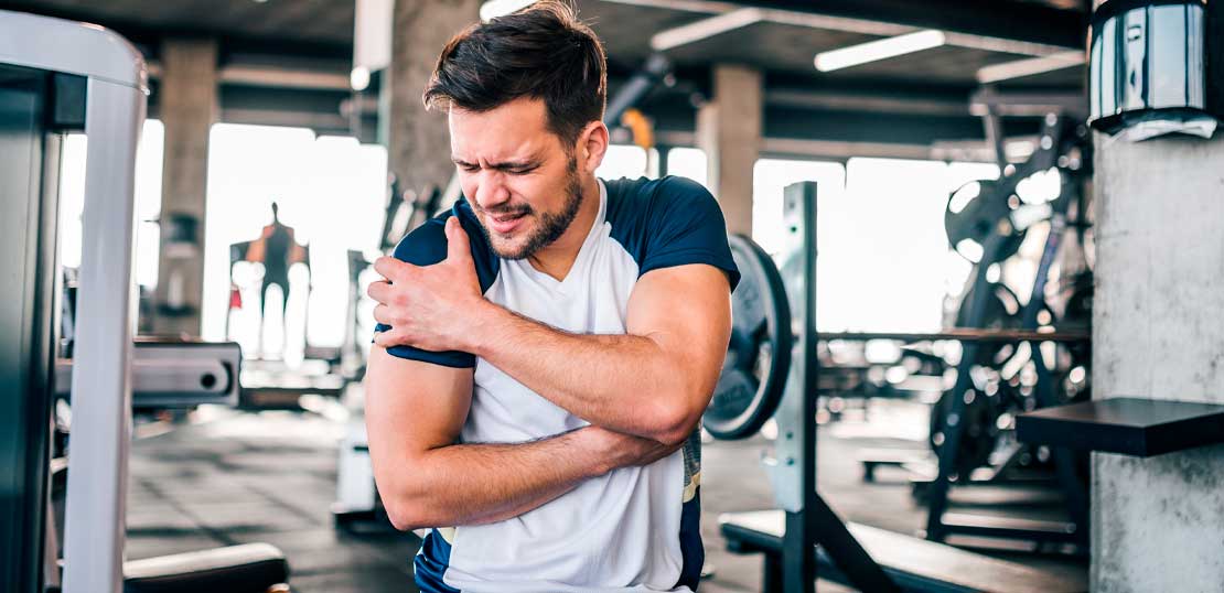 Portrait of a handsome man with strong facial expresion and injured arm while exercising in the gym.