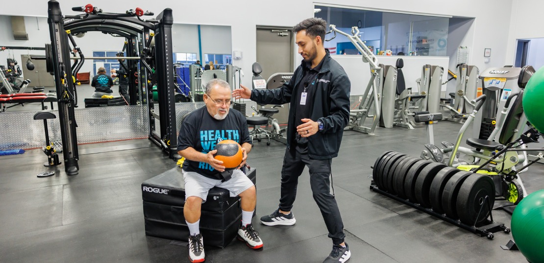 XO Physical therapist support to another during a workout, focusing on functional therapy exercises.